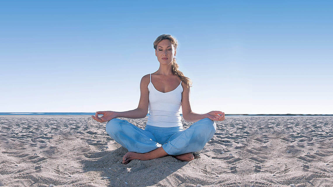 Frau beim Yoga am Strand